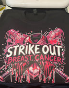 Black t-shirt with 'Strike Out Breast Cancer' design on a table.