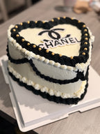 Heart-shaped cake with Chanel logo on a table