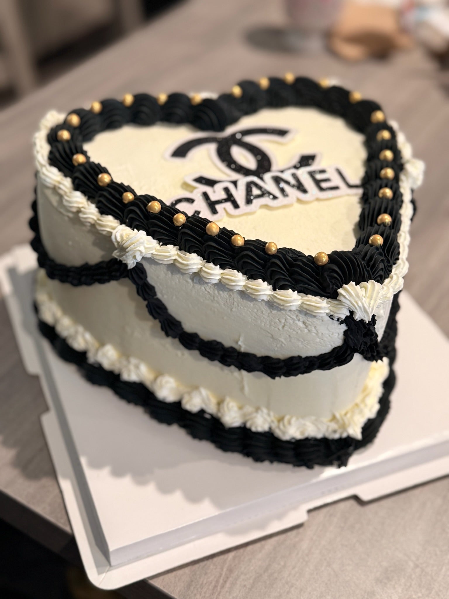 Heart-shaped cake with Chanel logo on a table